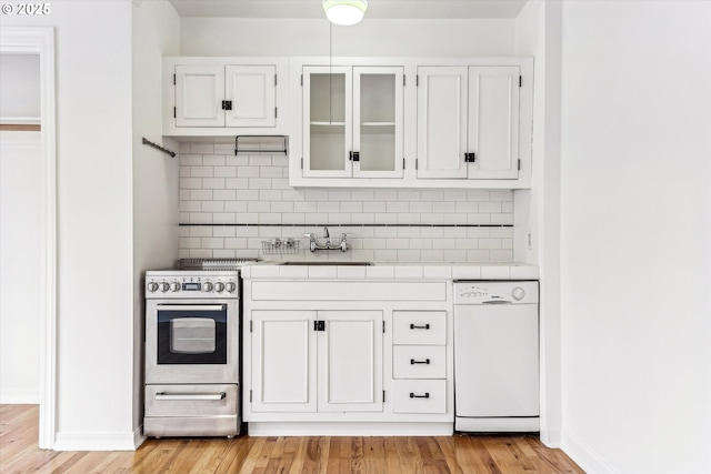 kitchen with tile counters, dishwasher, stainless steel electric range oven, light wood-type flooring, and backsplash