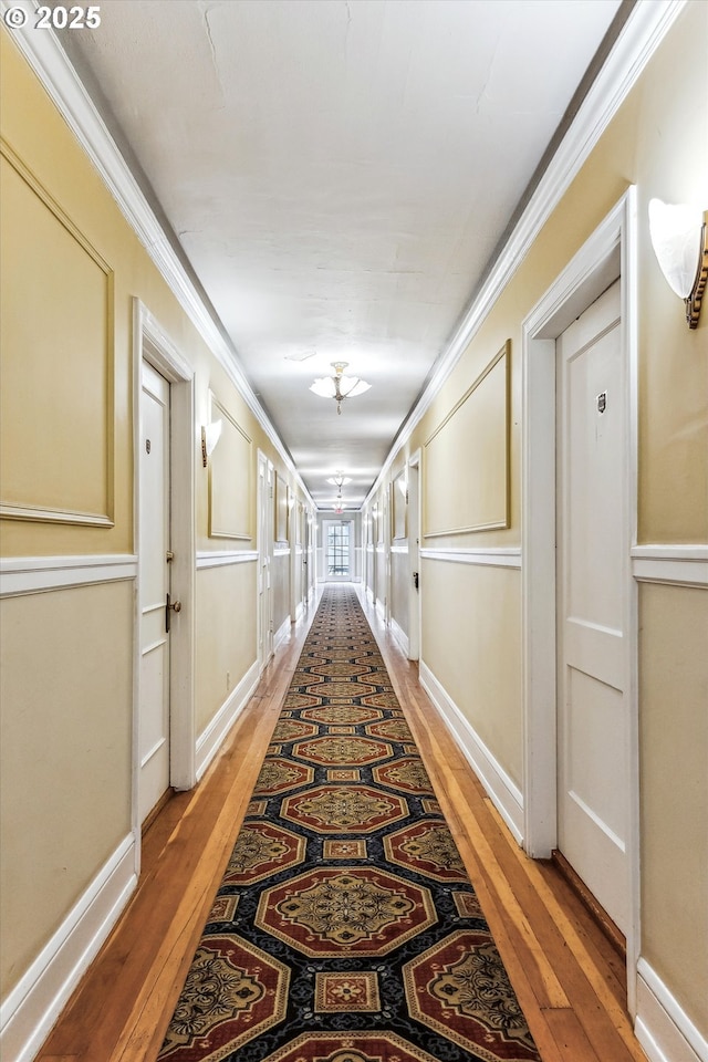 hall featuring baseboards, ornamental molding, and light wood-style floors