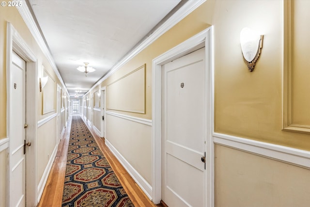 corridor with ornamental molding and light wood finished floors