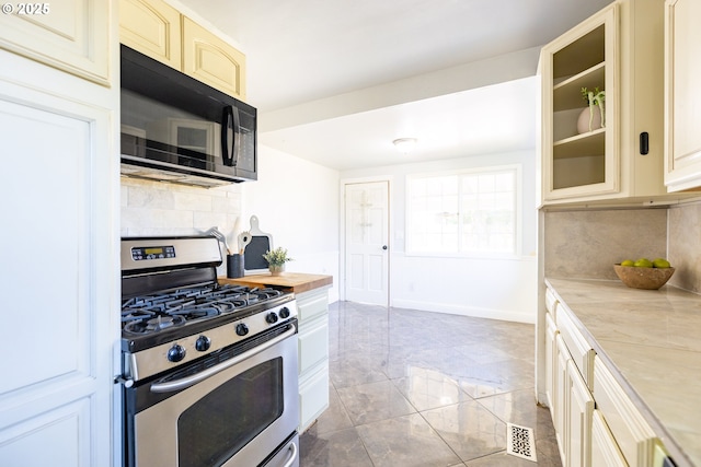 125 NE 80th Ave, Portland, OR 97213 - kitchen featuring black microwave, stainless steel gas stove, cream cabinetry, tasteful backsplash, and glass insert cabinets
