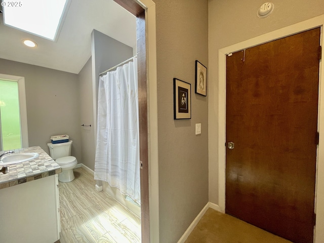 755 17th Ave, Coos Bay, OR 97420 - bathroom with vanity, toilet, a skylight, baseboards, and vaulted ceiling