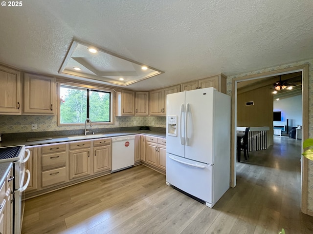 kitchen with white appliances, a sink, light brown cabinetry, light wood finished floors, and a textured ceiling