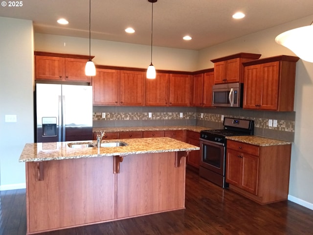 kitchen featuring stainless steel appliances, dark wood finished floors, a kitchen island with sink, and a sink