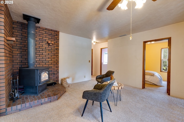 living area with a textured ceiling, carpet floors, a wood stove, and a healthy amount of sunlight