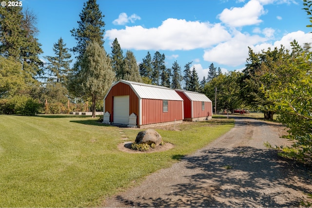 view of home's exterior featuring an outbuilding, metal roof, a garage, a gambrel roof, and a yard