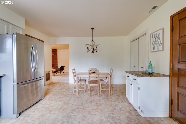 kitchen with visible vents, white cabinets, freestanding refrigerator, hanging light fixtures, and a chandelier