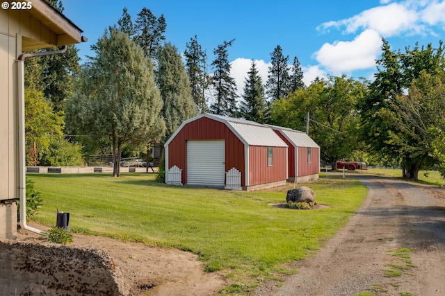 view of pole building featuring driveway, fence, and a lawn