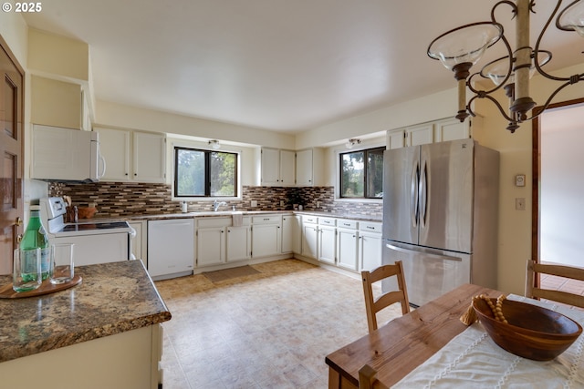 kitchen featuring light floors, decorative backsplash, white cabinetry, a sink, and white appliances