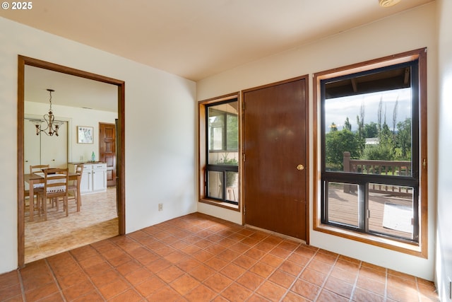 empty room featuring tile patterned flooring and a notable chandelier