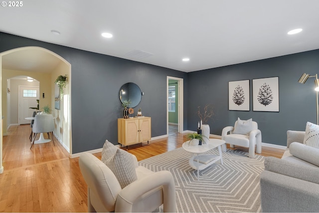 living area featuring recessed lighting, arched walkways, light wood finished floors, and visible vents