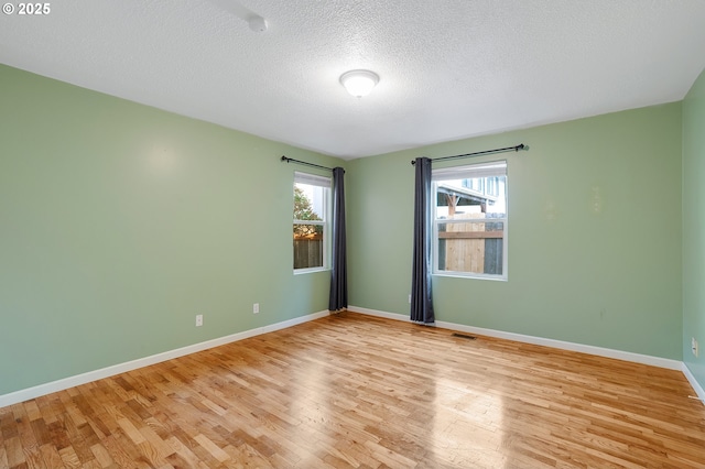 empty room with baseboards, a textured ceiling, and light wood-style flooring