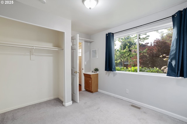unfurnished bedroom with baseboards, light carpet, a closet, and visible vents
