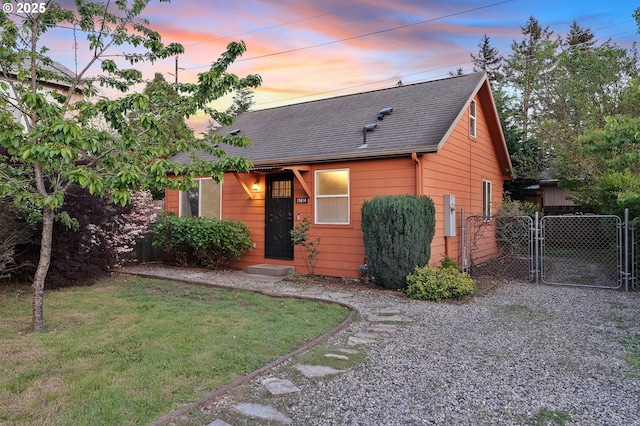 view of front facade with a gate, a front yard, and a shingled roof