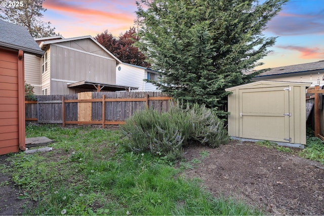 yard at dusk with fence, an outdoor structure, and a shed