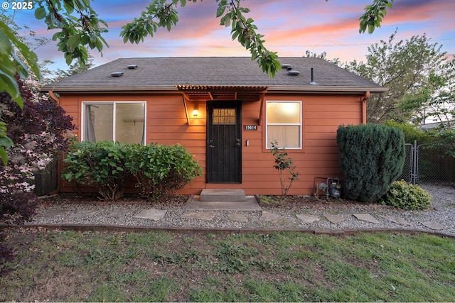 view of front of property with roof with shingles and fence