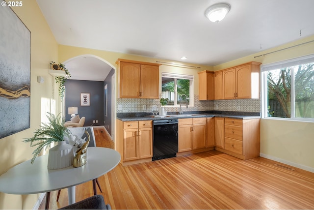 kitchen featuring visible vents, light wood-style floors, black dishwasher, tasteful backsplash, and a sink
