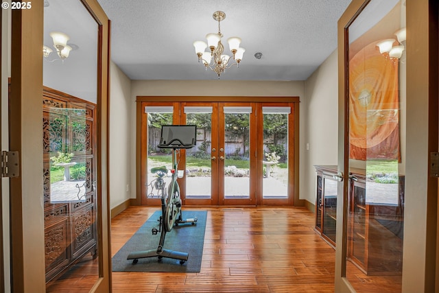 180 NW 107th Ave, Portland, OR 97229 - workout room featuring french doors, a chandelier, wood-type flooring, baseboards, and a textured ceiling
