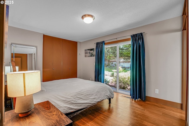 180 NW 107th Ave, Portland, OR 97229 - bedroom with wood finished floors, access to outside, a textured ceiling, and baseboards