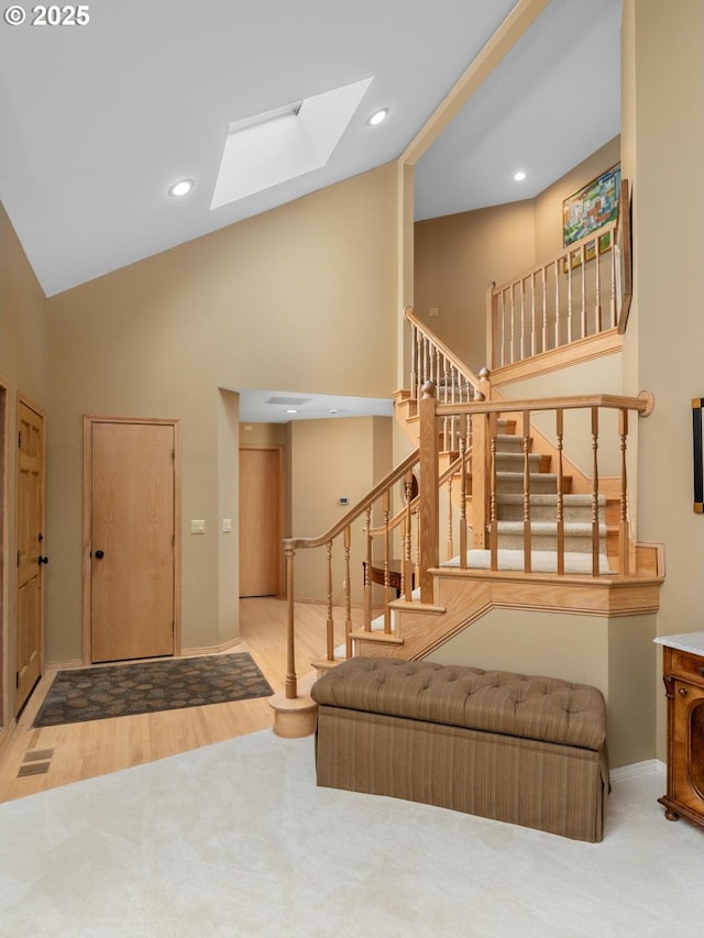 13910 SW Secretariet Ct, Beaverton, OR 97008 - entrance foyer featuring high vaulted ceiling, a skylight, stairway, carpet flooring, and wood finished floors