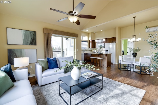 living room featuring high vaulted ceiling, dark wood-type flooring, and ceiling fan with notable chandelier