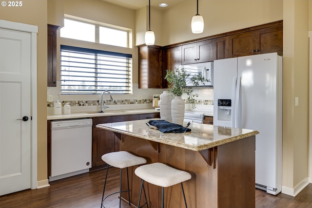 kitchen with white appliances, tasteful backsplash, a kitchen island, dark wood-style flooring, and a sink