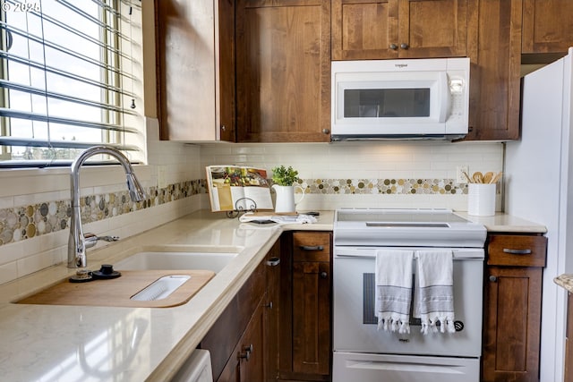 kitchen featuring white appliances, backsplash, and a sink