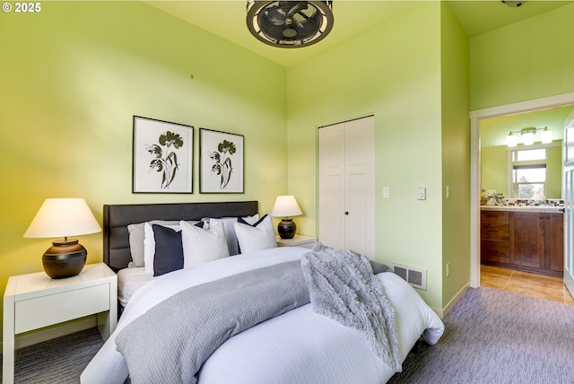 carpeted bedroom featuring a closet, visible vents, and ensuite bath