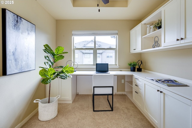 office featuring a ceiling fan, a raised ceiling, built in study area, and baseboards