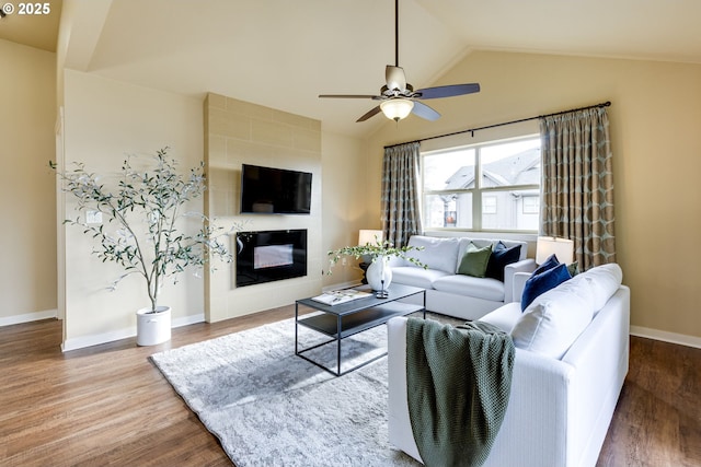 living area featuring lofted ceiling, ceiling fan, a fireplace, and wood finished floors