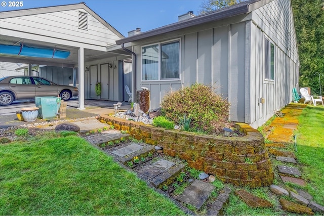 view of front of house featuring a carport, a front yard, board and batten siding, and a chimney