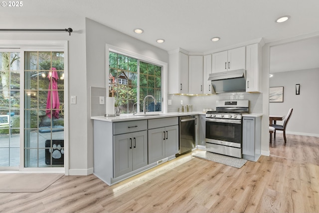 kitchen with a sink, light countertops, appliances with stainless steel finishes, backsplash, and gray cabinets