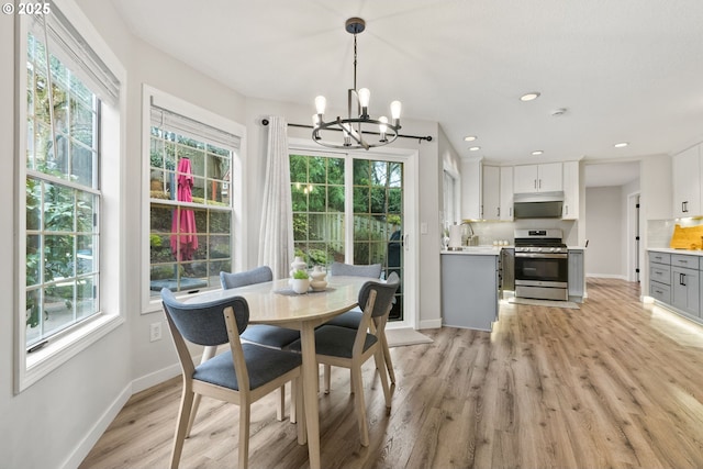 dining space featuring an inviting chandelier, light wood-style flooring, baseboards, and recessed lighting