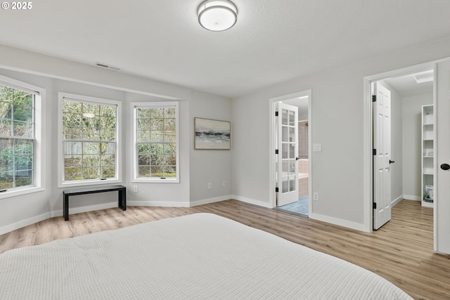 unfurnished bedroom featuring light wood-type flooring, visible vents, baseboards, and ensuite bathroom