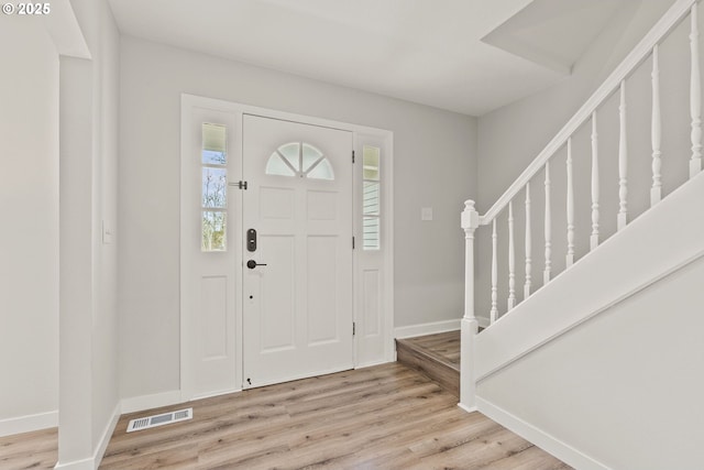 entryway featuring visible vents, light wood-style flooring, baseboards, and stairs