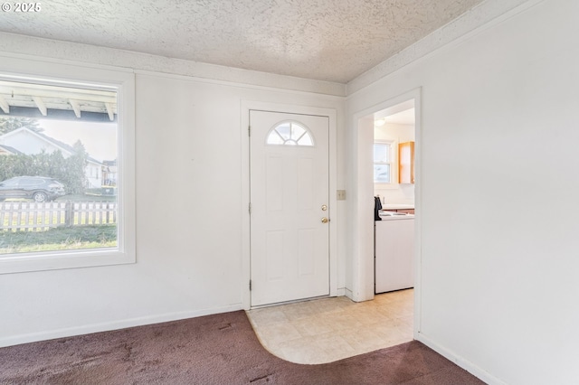 carpeted foyer featuring a healthy amount of sunlight, washer / dryer, and a textured ceiling