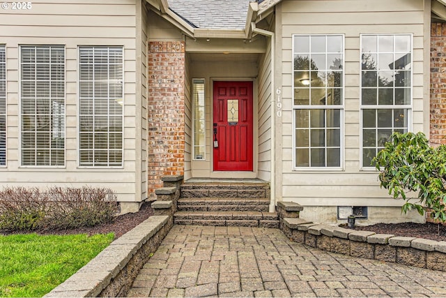 entrance to property featuring brick siding, crawl space, and a shingled roof