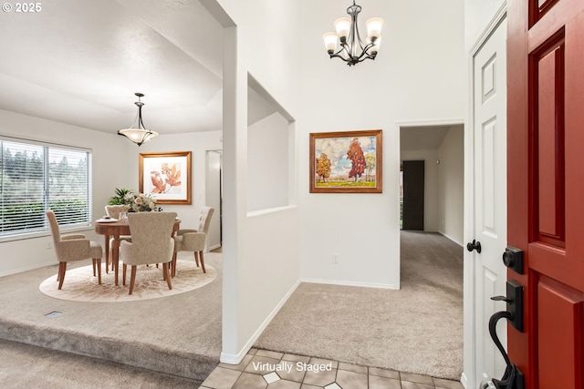 foyer entrance featuring light tile patterned floors, baseboards, a chandelier, and light colored carpet