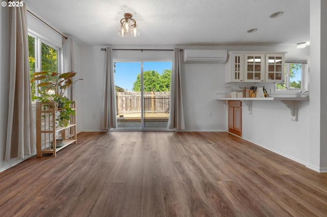 11144 NE Knott St, Portland, OR 97220 - unfurnished dining area featuring a wall mounted AC, wood finished floors, and healthy amount of natural light