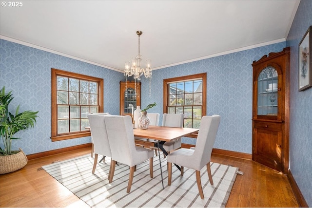 dining space with crown molding, hardwood / wood-style flooring, and an inviting chandelier