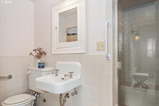 bathroom with a shower with door, tile walls, and toilet