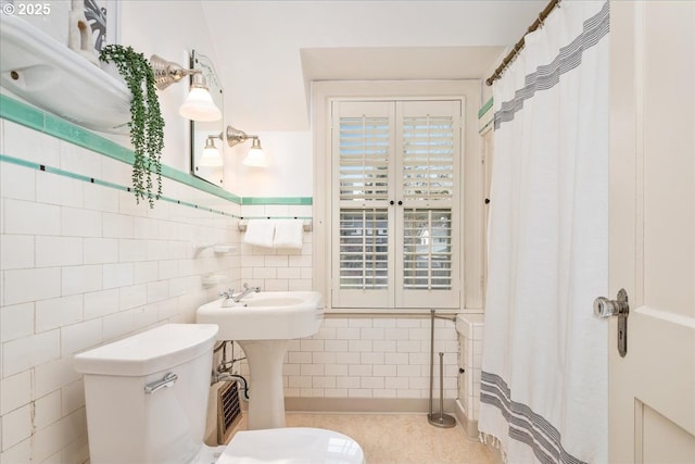 bathroom featuring toilet, a shower with shower curtain, and tile walls