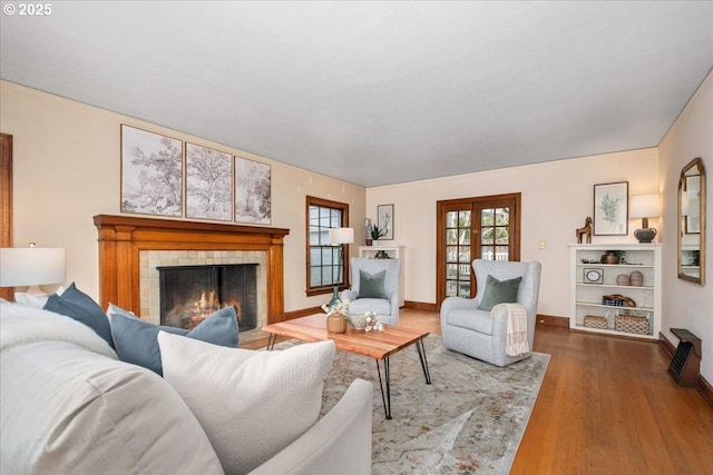 living room with a tile fireplace, wood-type flooring, and french doors