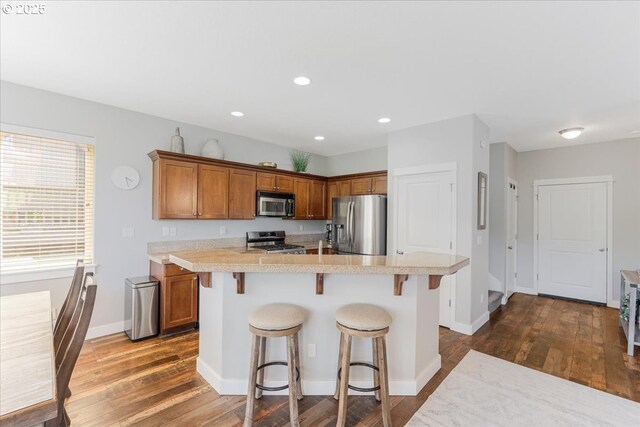 9050 SW 161st Ave, Beaverton, OR 97007 - kitchen with stainless steel appliances, brown cabinetry, dark wood-style floors, light countertops, and recessed lighting
