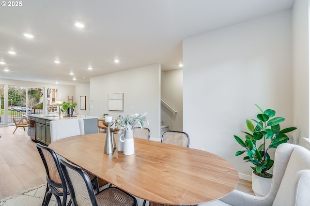 dining area with baseboards, light wood finished floors, recessed lighting, and stairs