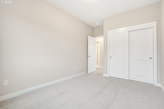 unfurnished bedroom with baseboards, carpet flooring, and a closet