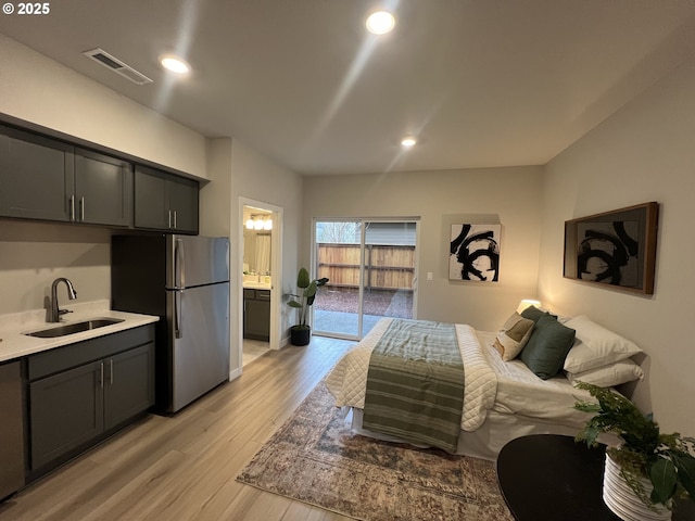 bedroom featuring visible vents, freestanding refrigerator, light wood-style floors, recessed lighting, and a sink