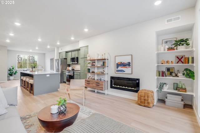 living area with recessed lighting, visible vents, and light wood-style floors