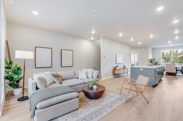 living room with recessed lighting, baseboards, and light wood-type flooring