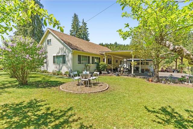 rear view of house featuring a yard, a patio, and roof with shingles