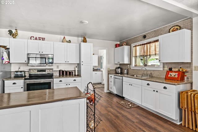 kitchen featuring appliances with stainless steel finishes, a sink, dark wood-type flooring, backsplash, and white cabinetry
